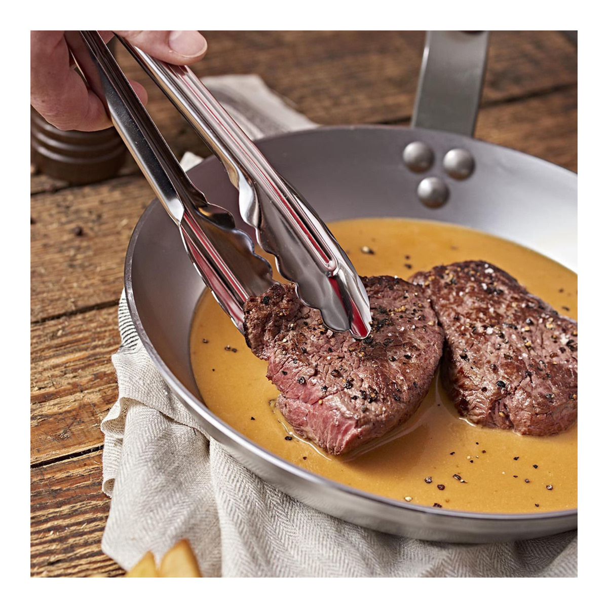 Pince de cuisine en inox utilisée pour saisir une viande