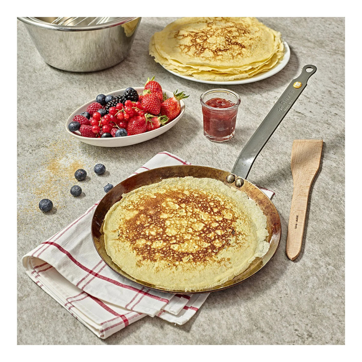 Poêle à crêpes en acier avec crêpe et fruits rouges