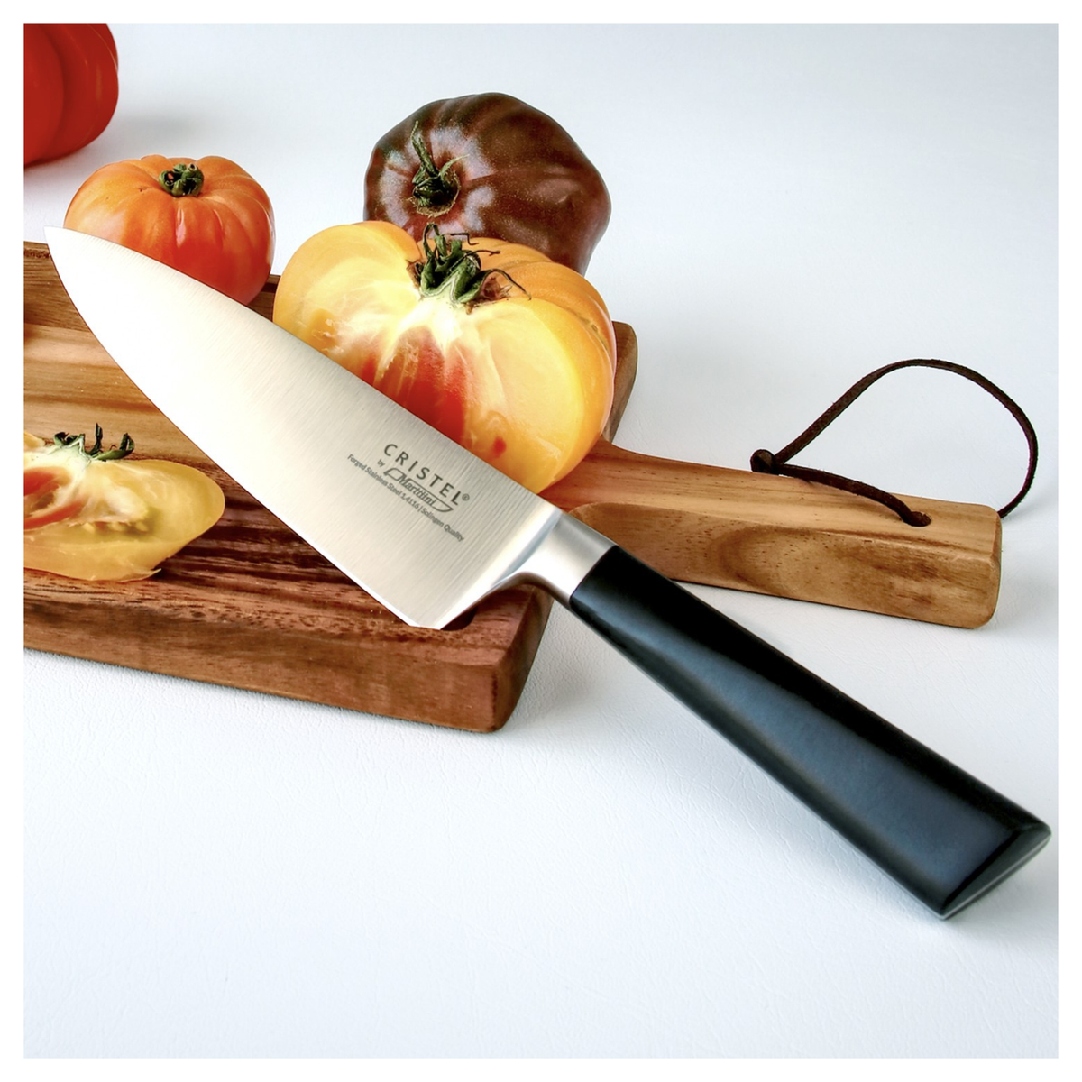 Couteau de chef Cristel présenté avec des tomates sur planche en bois