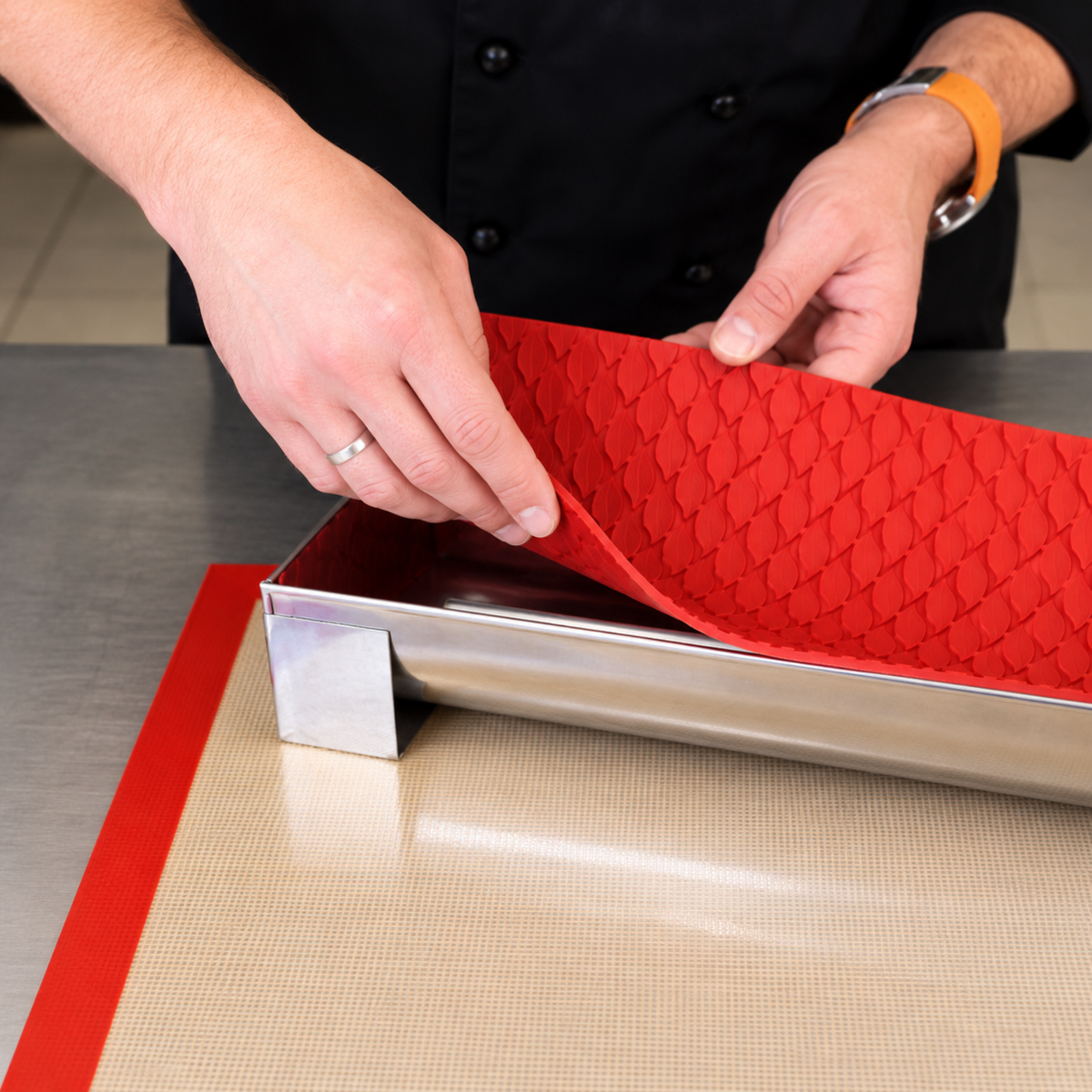 Tapis décor silicone rouge effet tricot placé dans un moule à bûche inox
