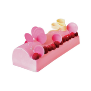Bûche de Noël rose au glaçage brillant, décorée de framboises fraîches, de disques roses et de volutes en chocolat blanc.