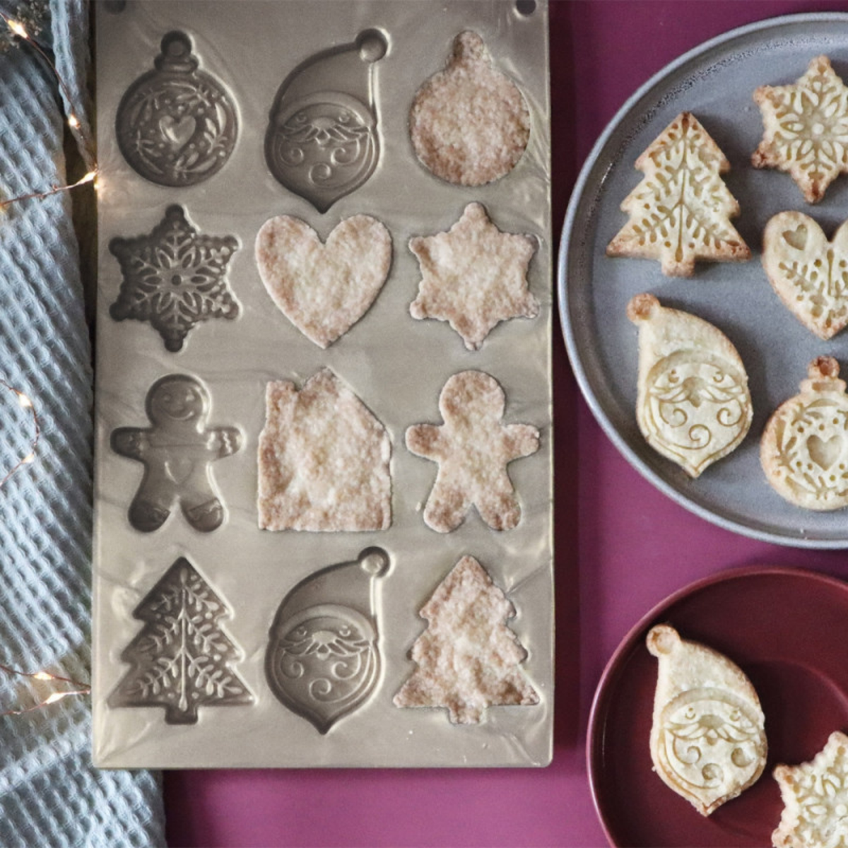 Moule silicone ScrapCooking à 12 empreintes de Noël avec biscuits sablés démoulés et décorés, présentés sur des assiettes.