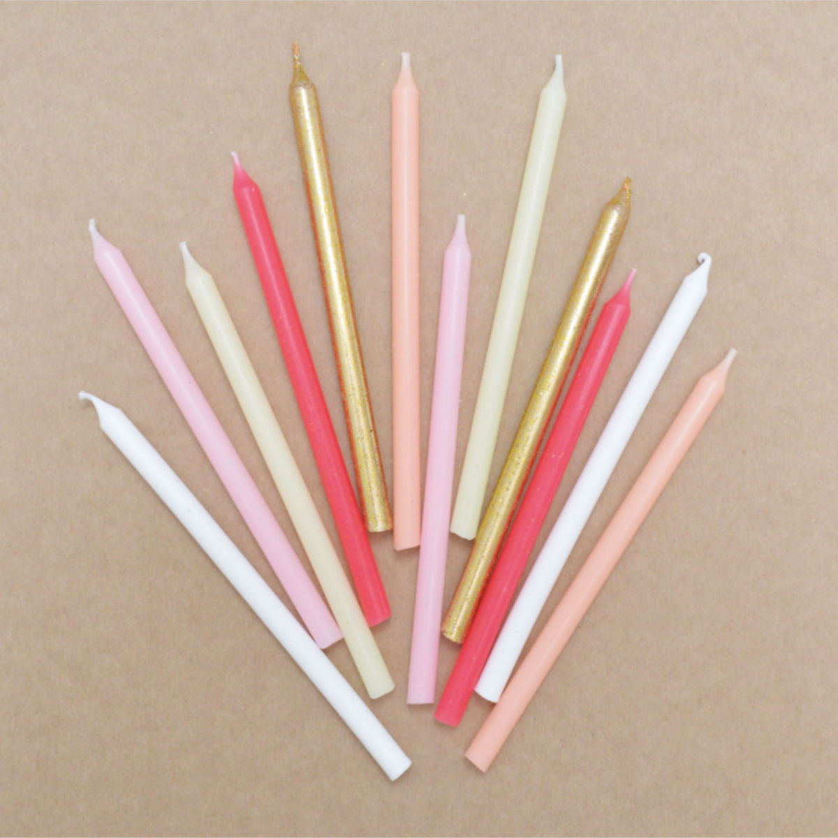 Assortiment de 12 bougies d’anniversaire longues ScrapCooking rose et or, disposées en éventail sur fond beige.