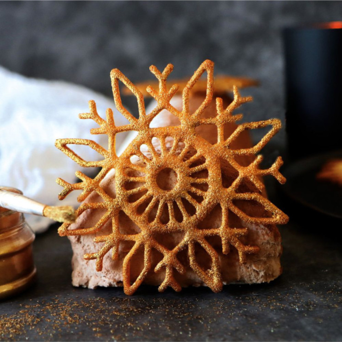 Tuile pâtissière en forme de flocon de neige ajouré, recouverte de poudre dorée, réalisée avec un tapis en silicone ScrapCooking.
